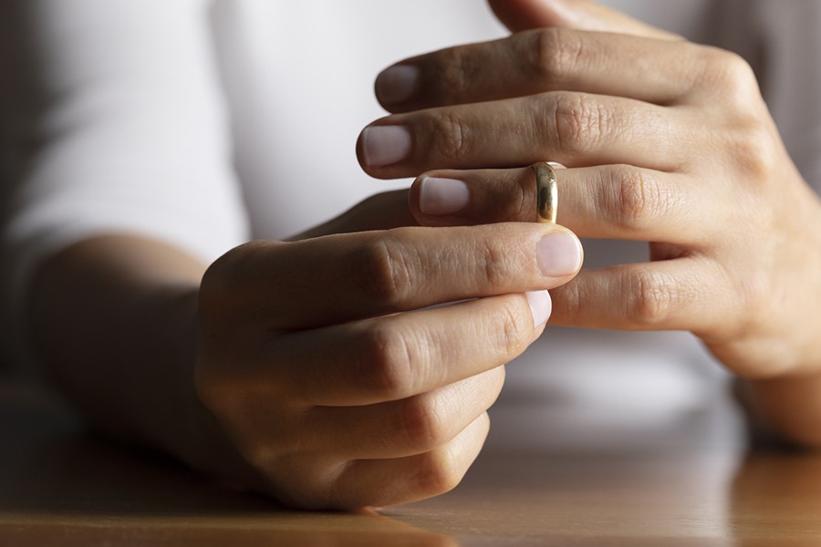 Hands of caucasian female who is about to taking off her wedding ring.